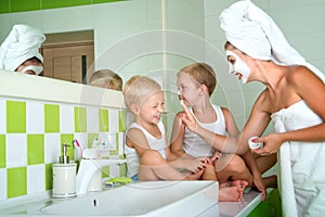 Mother and children make a face mask in the morning. The boys joke with mom.