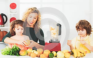 Mother with children making smoothie in a white kitchen. Family mother and child daughter and son blended smoothie with