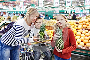 Mother and children with pineapples in fruit department of super
