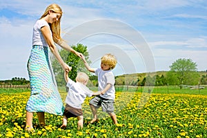 Mother and Children Playing and Dancing Outside in Flower Meadow