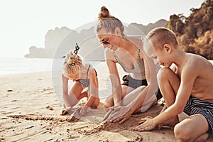 Mother and children playing on a sandy beach during vacation