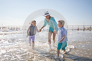 Mother and children are playing in the sea on the beach