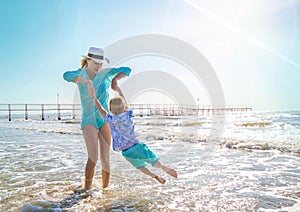 Mother and children are playing in the sea on the beach