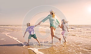 A mother and children are playing in the sea on the beach