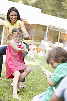 Mother And Children Playing Tug Of War