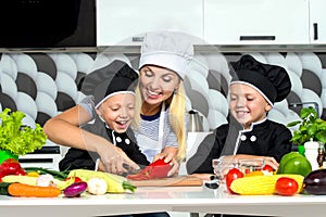 A family of cooks.Healthy eating.Mother and children prepares vegetable salad in kitchen.