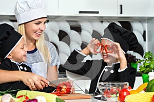 A family of cooks.Healthy eating.Mother and children prepares vegetable salad in kitchen.