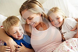 Mother And Children Relaxing Together In Bed