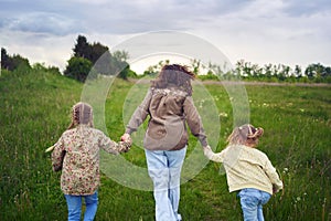 mother and children run holding hands in the field