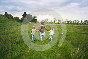 mother and children run holding hands in the field