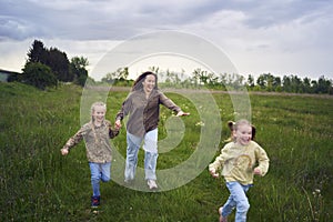 mother and children run holding hands in the field