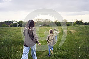 mother and children run holding hands in the field
