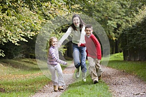 Mother and children running along woodland path