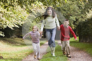 Mother and children running along woodland path