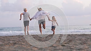 A mother with children runs to the sea holding hands