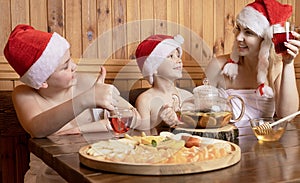 Mother with children in Santa hats drinking tea in the sauna . Healthy lifestyle.New Year, Christmas.