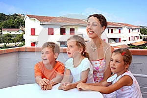 Mother and children sit in day-time on balcony