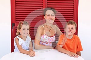 Mother with children sit near shut door to table