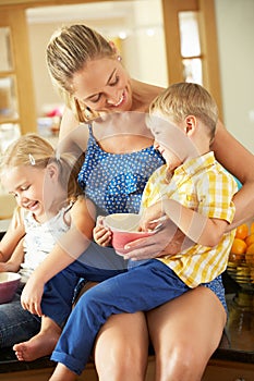 Mother And Children Sitting On Kitchen Counter