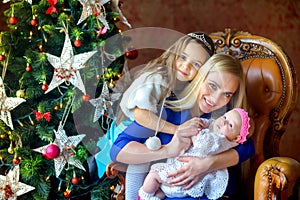 Mother with children sitting near the Christmas tree, waiting for the holiday