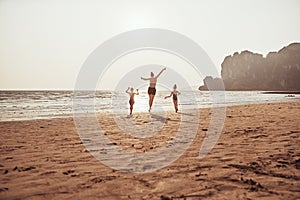 Mother and children skipping on a sandy beach during vacation