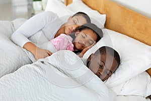 Mother and children sleeping together in bed in bedroom