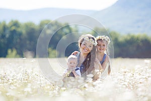 Mother with children in a summer field of blooming daisies