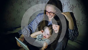 Mother and children with a tablet computer at home watching cartoons and playing