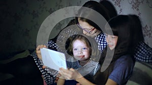 Mother and children with a tablet computer at home watching cartoons and playing