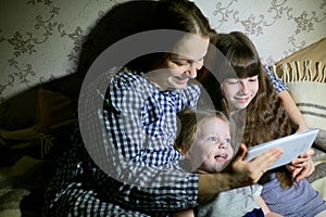 Mother and children with a tablet computer at home watching cartoons and playing