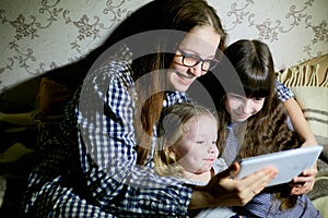 Mother and children with a tablet computer at home watching cartoons and playing