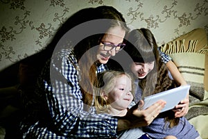 Mother and children with a tablet computer at home watching cartoons and playing