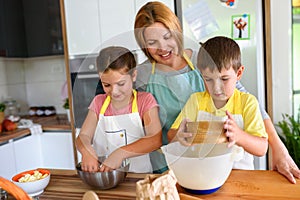 Mother and children together making apple pie in the kitchen at home. Children helping mother