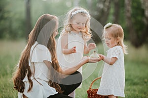 Mother and children two little daughters having fun in a meadow. Summer, nature, family, vacation. mother`s, baby`s day