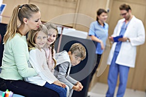 Mother and children waiting in front of registration desk in hospital