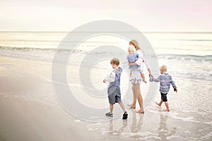 Mother and Children Walking Along Ocean Beach at Sunset