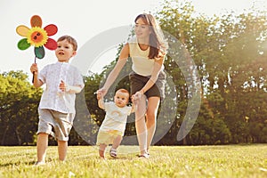 Mother and children are walking in the park at sunset.