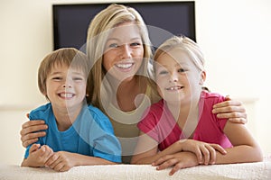 Mother And Children Watching Widescreen TV At Home