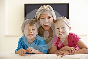 Mother And Children Watching Widescreen TV At Home