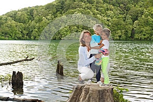 mother and children on a wooden stump next to the untouched fore