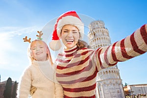 Mother in Christmas hat taking selfie with daughter in Pisa