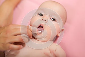 Mother cleaning baby`s mouth with special fingertip brush photo