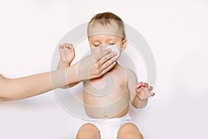 Mother cleaning eyes of a newborn baby with physiological solution on a cotton disk