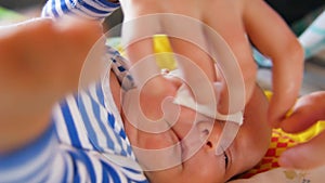 Mother cleaning eyes of a newborn baby with physiological solution on a cotton strip