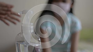 Mother cleaning her hands with alcohol gel and wearing protective mask before approach and combing her daughter`s hair.