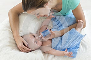 Mother cleaning nose mucus of adorable baby with a nasal aspirator photo