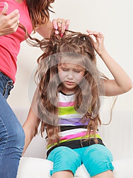 Mother combing hair for daughter