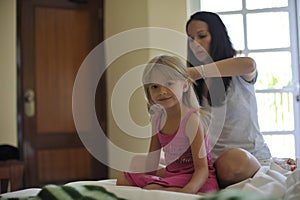 Mother combing the hair of her daughter.