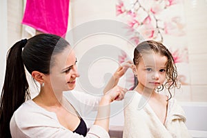 Mother combing hair of her daughter after taking bath