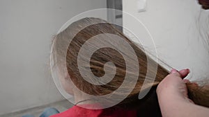 Mother combs her daughter's hair. Woman is brushing her lovely daughters hair.